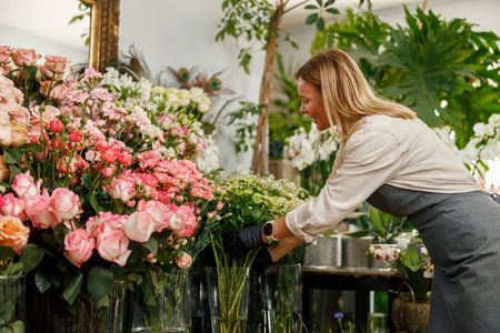 Smiling woman florist small business owner standing in own floral store and waiting for clientの写真素材
