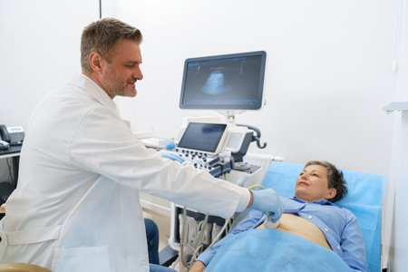 Male sonographer doing abdominal ultrasound scanning for woman patient in medical clinic