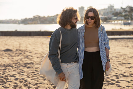 Handsome couple in love hugging while walking along the beach on sunny day