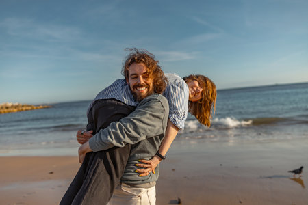 Smilng couple in love fool around while walking along the beach on sunny windy dayの写真素材