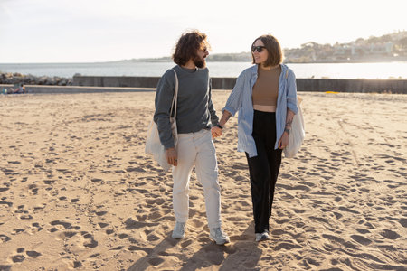 Happy romantic couple in love is walk holding hands across the sunny beachの写真素材