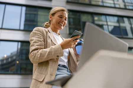 Businesswoman is using phone and work on laptop outside of office. Distance work concept