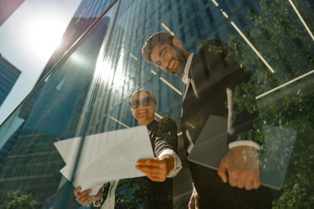 Bottom view of business partners working with documents standing outside of office and drink coffeeの写真素材
