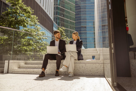 Contemporary businessman and businesswomen working outdoor on laptop with new startup projectの写真素材