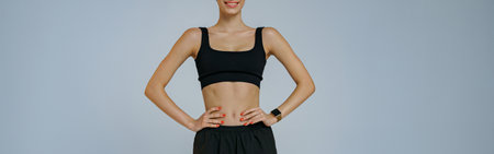Portrait of smiling fitness woman wearing sportswear looking at camera on studio backgroundの写真素材