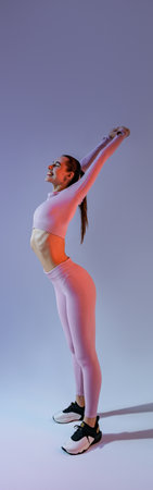 Athletic woman wearing sportswear doing warm-up before training session in gym on studio background