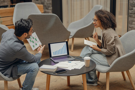 Stylish male manager showing business plan to colleague during work in office