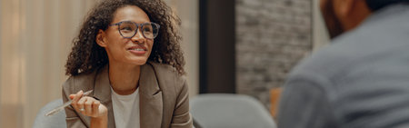 Smiling female manager is making notes during meeting with colleague in coworking spaceの写真素材