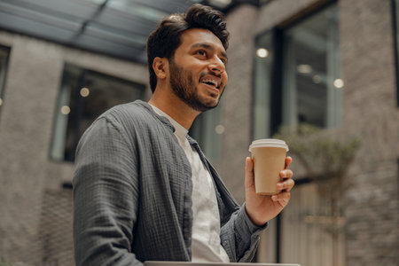 Handsome businessman is standing on office background and drinking coffeeの写真素材