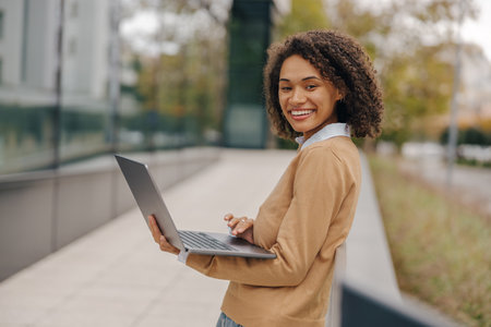 Smiling woman manager working laptop on modern building background and looks cameraの写真素材