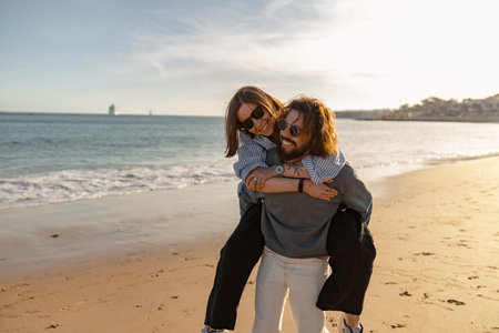 Smiling romantic couple in love hugging while walking along the beach on sunny dayの写真素材