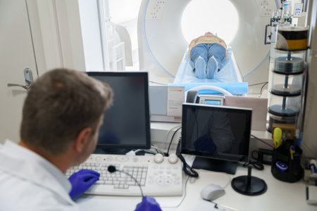 Doctor radiologist controls MRI or CT or PET Scan with female patient undergoing procedureの写真素材