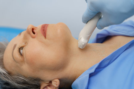 Middle aged woman patient during ultrasound examination of thyroid lying on couch in medical office