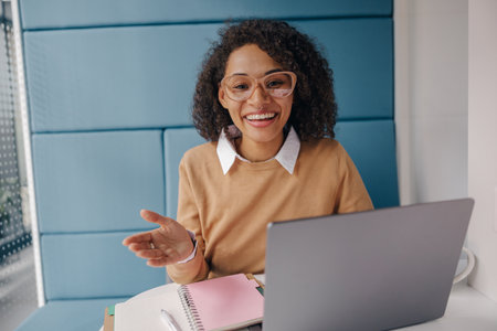Smiling business woman using laptop while sitting on modern office background
