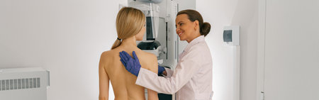 Smiling doctor prepairing woman before doing mammogram x-ray to check for breast cancer at hospital