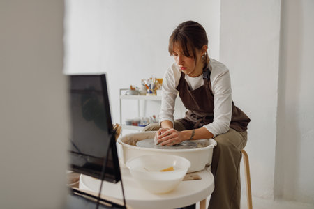 Professional female artisan shaping clay bowl in pottery studio. Ceramics art concept