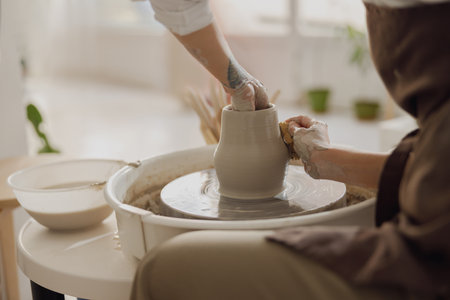 Close up of hands of professional potter molding pot shape on pottery wheel. Ceramics art conceptの写真素材