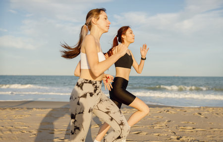 Young athletic women in sportswear is jogging along shore of beach. Concept of healthy living