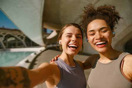 Young smiling female sportswomen have a rest after morning jogging outdoors and looks cameraの写真素材