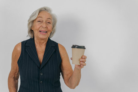 A Cheerful Senior Woman is Enjoying Her Coffee in a Relaxing and Joyful Atmosphereの写真素材