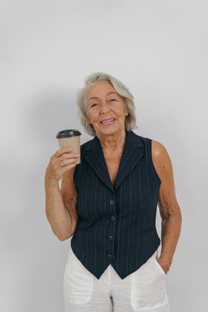 A Happy Elderly Woman Relishing a Delicious Cup of Coffee While Dressed in Casual Attire
