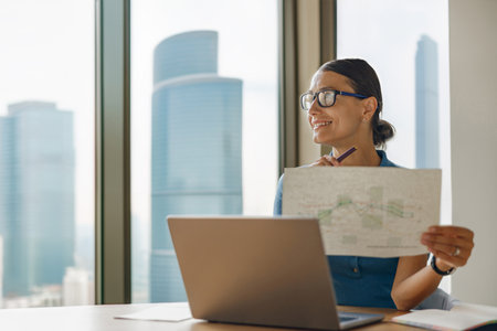 A skilled businesswoman is presenting key data in a modern office, showcasing her expertiseの写真素材