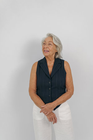 An Elegant Senior Woman Dressed in Casual Attire Who is Smiling Cheerfully and Gracefullyの写真素材