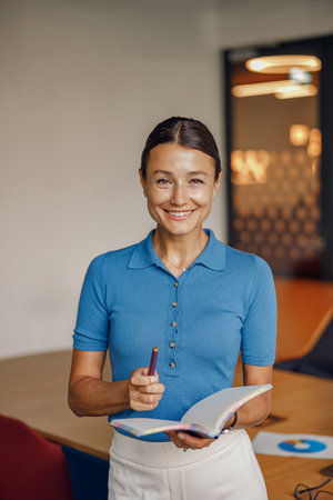 A Smiling Professional Woman Working in a Bright and Modern Workspace Environment Setupの写真素材