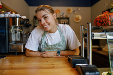 A friendly barista greets customers at a cozy cafe with a warm and inviting ambianceの写真素材