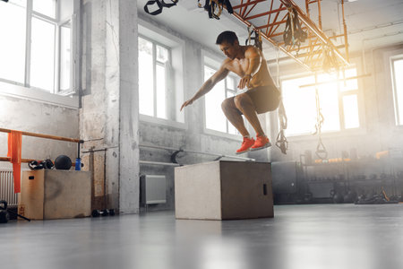An athlete is energetically performing a challenging box jump in a modern fitness studio settingの写真素材