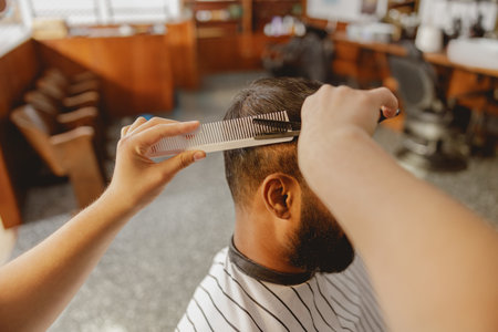 A skilled barber expertly cuts hair with precision tools in a cozy, welcoming barbershopの写真素材
