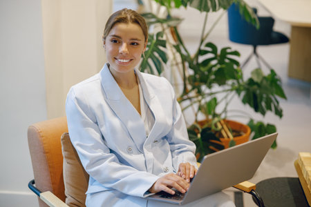 A Professional Woman Diligently Working on Her Laptop in a Modern Office Environment