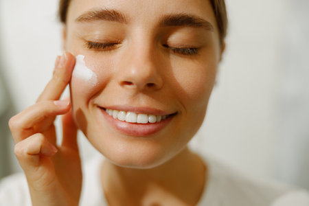 Skincare Routine Happy Woman Joyfully Applying Moisturizer in Her Bathroom Areaの写真素材