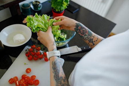 Preparing fresh salad ingredients in a modern kitchen with careful attention to detailの写真素材