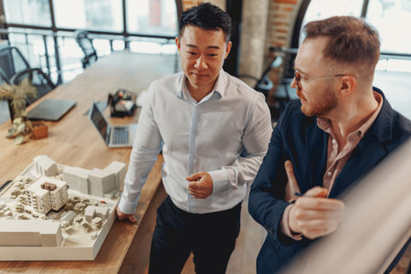 Architects discuss a project model in a modern office, highlighting collaboration and innovationの写真素材