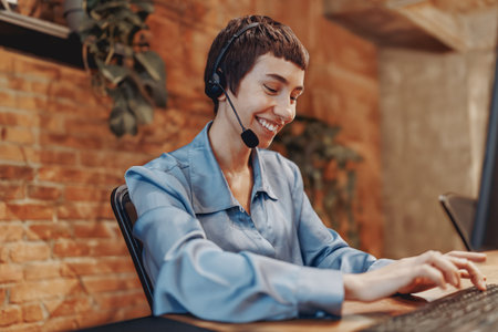A dedicated professional woman wearing a headset is actively engaged in her work at the deskの写真素材