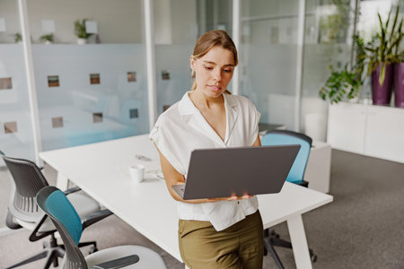 A Young Professional, Engaged in Work on a Laptop within a Stylish, Modern Office Setting