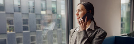 A Professional Woman Engaged in a Phone Conversation within a Modern Office Environment