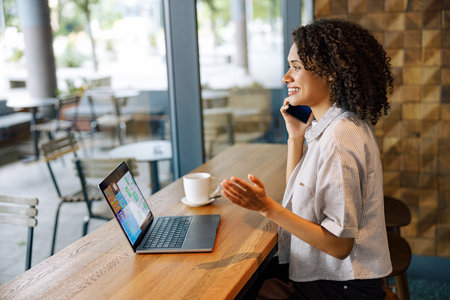 Woman Engaged in Conversation at a Caf Table with Laptopの写真素材