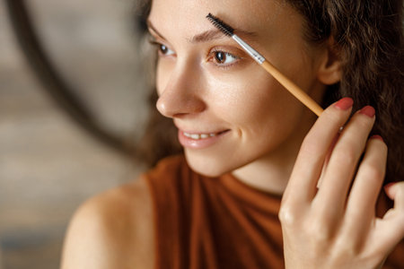 A Woman Carefully Applying Eyebrow Makeup in Beautiful Natural Light for a Radiant Look