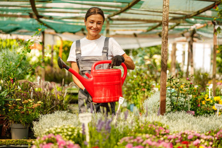 A happy gardener is joyfully watering vibrant plants in a delightful flower nursery settingの写真素材