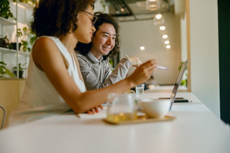 team discussing information over coffee, employees sharing insights while working at their workspaceの写真素材
