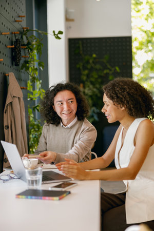 colleagues revise digital project together, two coworkers discussing ideas using technology toolsの写真素材