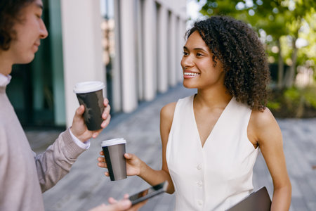 urban colleagues chatting, individuals in modern attire share relaxed moment outside of theirの写真素材