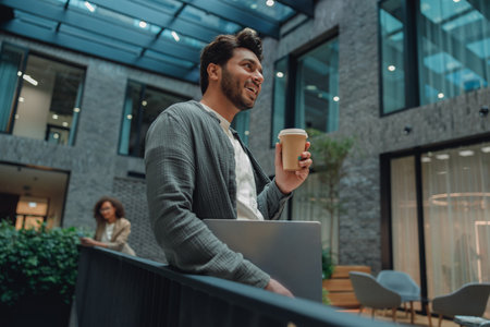 male worker relaxing, professional man with coffee, businessman enjoying morning chill in coworking areaの写真素材