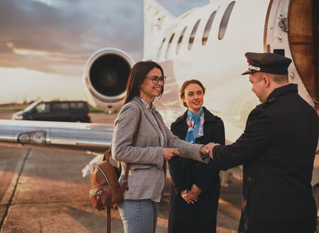 Private Jet Boarding Experience Female Traveler Handing Document to Pilot Beside Aircraft Door While Flight Attendant Smiles in Dramatic Sunset Sky
