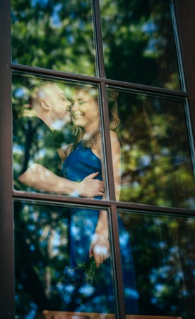 Lovely young couple in the window. View through the glass.の写真素材