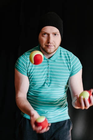 Man in a cap, juggling with several balls at once.の写真素材