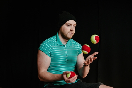 A man in a hat, juggling with several balls at once.の写真素材