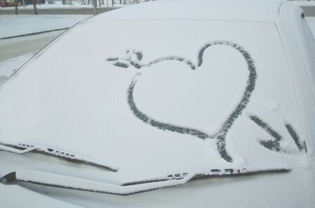 Drawing a heart on a snowy car, valentine's day concept.の写真素材